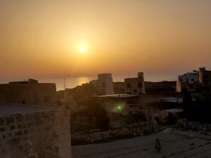 a sunset over a city with buildings and the ocean at Azure W B&B in San Lawrenz