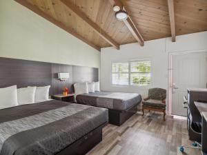 a hotel room with two beds and a chair at Discovery Inn Monterey Bay in Seaside