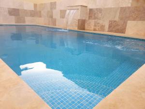 a swimming pool with a blue tiled floor and a water fountain at Azure W B&B in San Lawrenz