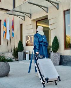 a woman walking with her luggage in front of a building at 21 Rooms Hotel in Gyumri