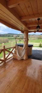 eine Hängematte auf einer Veranda mit Blick auf ein Feld in der Unterkunft Góralskie Domki na Podhalu - z jacuzzi in Maniowy