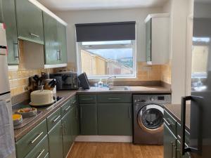 a kitchen with green cabinets and a washing machine at Walk to town,child friendly,free parking in Kingsbridge