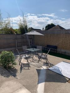 a patio with a table and chairs and an umbrella at Hafan Traeth in Prestatyn