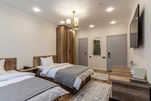 a bedroom with two beds and a desk with a laptop at Oscar Hotel by AG Hotels Group in Almaty