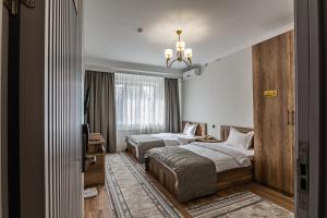 a hotel room with two beds and a chandelier at Oscar Hotel by AG Hotels Group in Almaty