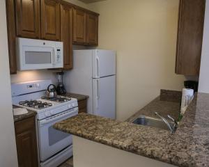a kitchen with a white refrigerator and a sink at Suites at Club De Soleil Las Vegas in Las Vegas
