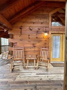 Tellico Plains的住宿－Romantic Laurel Wood Home with Private Hot Tub，小木屋前门廊上摆放着两把椅子和一张桌子