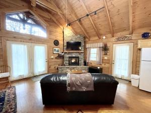 Tellico Plains的住宿－Romantic Laurel Wood Home with Private Hot Tub，客厅设有真皮沙发和壁炉