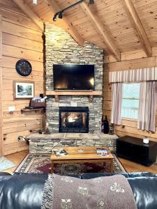 a living room with a stone fireplace and a television at Romantic Laurel Wood Home with Private Hot Tub in Tellico Plains +11 photos
