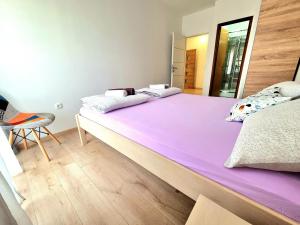 a bedroom with two beds with purple sheets and a chair at Julia in Biograd na Moru