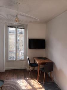 Zimmer mit einem Tisch, 2 Stühlen und einem TV in der Unterkunft Très Parisien et ensoleillé in Paris