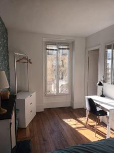 a white room with a desk and a table and window at Très Parisien et ensoleillé in Paris