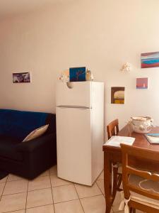 un frigorifero bianco in un soggiorno con tavolo di casa di Golfo Aranci mare a Golfo Aranci