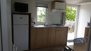 a kitchen with a refrigerator and a sink and a window at Camping La Berquerie in Le Mesnil-Réaume