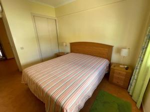 a small bedroom with a bed with a striped bedspread at Cabanas de Tavira Apartment in Cabanas de Tavira +35 photos