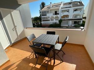 una mesa y sillas en un balcón con un edificio en Cabanas de Tavira Apartment, en Cabanas de Tavira