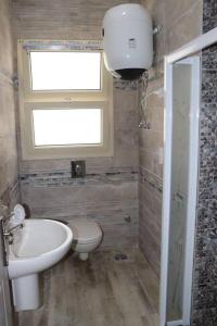 uma casa de banho com um lavatório, um WC e uma janela. em Hacienda Bay 4 bedrooms Chalet em El Alamein
