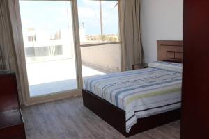 um quarto com uma cama e uma grande janela em Hacienda Bay 4 bedrooms Chalet em El Alamein