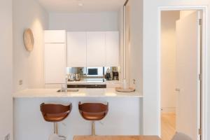 una cucina con armadi bianchi e 2 sgabelli da bar di Central Holborn Bloomsbury flats a Londra