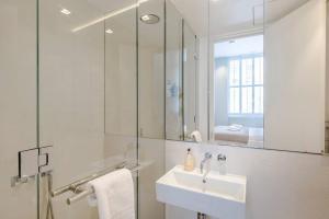 bagno bianco con lavandino e specchio di Central Holborn Bloomsbury flats a Londra