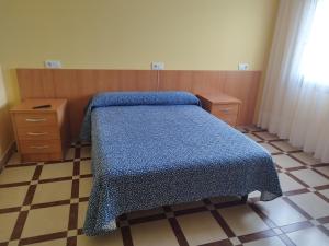 a bedroom with a bed with a blue blanket on it at Pension Pilar in Sanxenxo