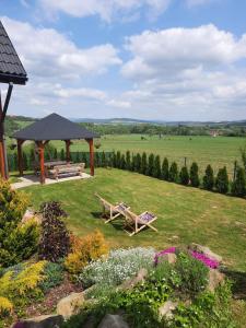 a garden with two benches and a gazebo at Domki pod Derkaczem in Wünschelburg