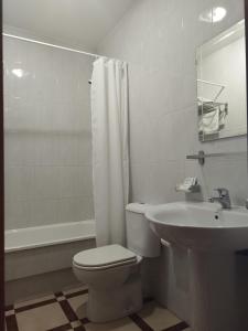 a white bathroom with a toilet and a sink at Pension Pilar in Sanxenxo