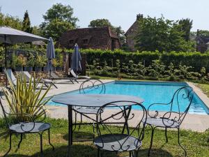 un tavolo e sedie accanto alla piscina di Château de Vassinhac chambres d'hôtes Collonges la rouge a Collonges