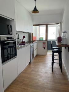 Matosinhos Terrace Apartment في ماتوسينهوس: مطبخ مع دواليب بيضاء وطاولة وكراسي