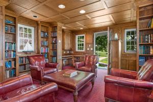 a library with leather chairs and a table and bookshelves at 25 Bedrooms - Retreat Center Waterfront Renovated in Royal Oak