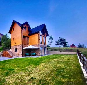 a house on a green field with a fence at LUX PINE house in Zlatibor