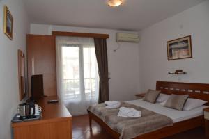 a bedroom with a bed and a desk and a television at Guest House Zec in Budva