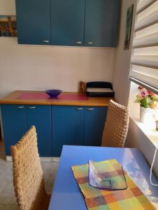 a kitchen with blue cabinets and a table and chairs at Lipov lad in Bela Crkva +2 photos