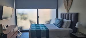 - une chambre avec un lit doté d'oreillers bleus et d'une fenêtre dans l'établissement Cozy Studio with WiFi & Netflix, à Playa del Carmen
