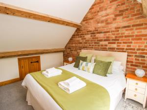 a bedroom with a bed with a brick wall at The Olde Cowshed in Acton Scott