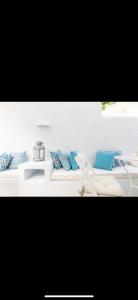 Un sofá blanco con almohadas azules. en Studios Eleni II, en Tinos