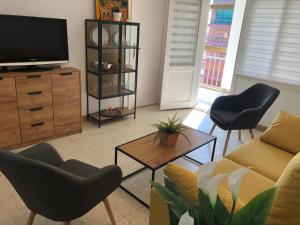a living room with a couch and chairs and a tv at Apartamento con vistas al mar, Punta Umbria in Punta Umbría