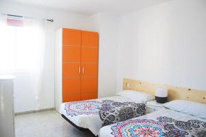 1 Schlafzimmer mit 2 Betten und einem orangefarbenen Schrank in der Unterkunft Casa Arya in Cotillo
