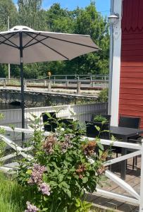 un patio con mesa, sombrilla y flores en Lovely Waterfront Cottage near Karlshamn en Asarum