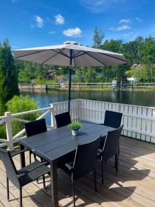 einem schwarzen Tisch mit Stühlen und einem Sonnenschirm auf einer Terrasse in der Unterkunft Lovely Waterfront Cottage near Karlshamn in Asarum