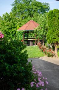 a gazebo with a bench in a garden with flowers at Apartman Mina 1 in Vrdnik