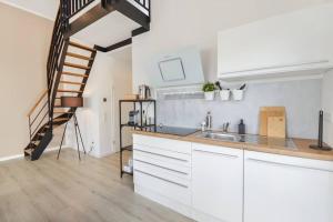 a kitchen with white cabinets and a staircase at AT WEINMEISTER - Luftig & leicht in Bielefeld