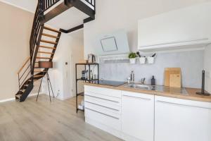 a kitchen with white cabinets and a staircase at Luftig, leicht & lebensfroh - Loft - Wifi - TV in Bielefeld