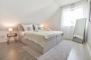 a white bedroom with a large bed and a mirror at Luftig, leicht & lebensfroh - Loft - Wifi - TV in Bielefeld