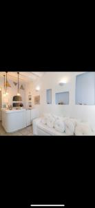 a living room with a white couch and a kitchen at Studios Eleni II in Tinos