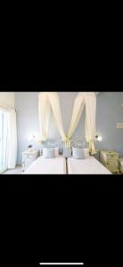 a bedroom with two beds with curtains hanging over them at Studios Eleni II in Tinos