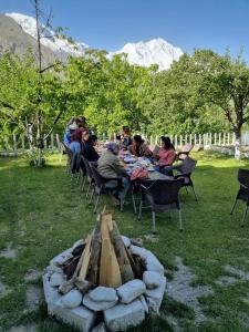 a group of people sitting at tables around a fire pit at Royal's Villa by Premiere Inn, Hunza in Hunza