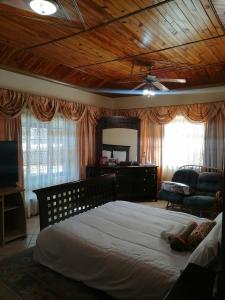 1 dormitorio con 1 cama grande y techo de madera en Tjibelu's Nest Guest Home, en Lobatse