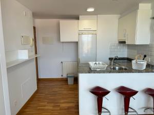 a kitchen with white cabinets and red stools at Playa Miño in Miño +10 photos