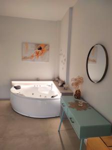 サン・メナイオにあるDeluxe Romantic Suiteのバスタブ、テーブル、鏡が備わります。